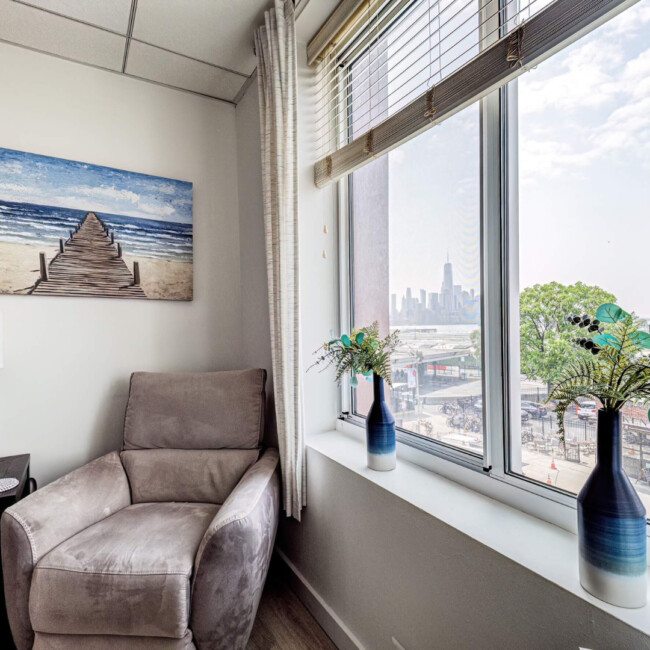 Room in Anchor Therapy office with a chair and large widow with a view of the Manhattan skyline.