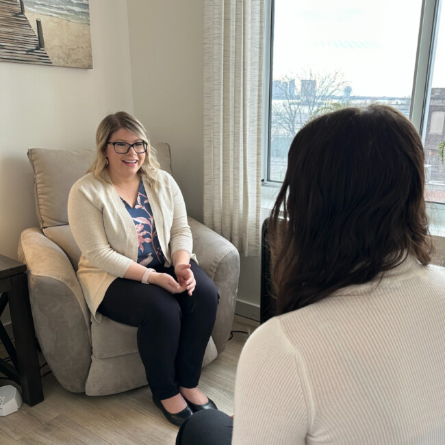 Courtney Glashow, LCSW sitting in a chair speaking to a client.