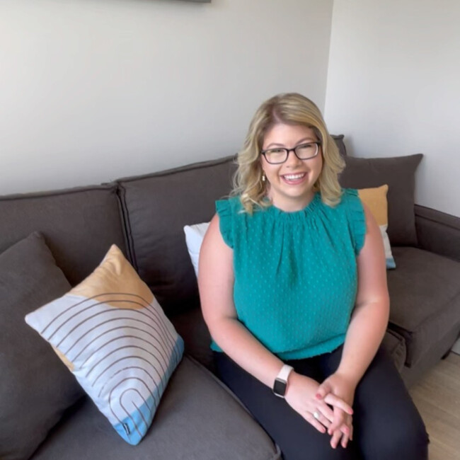 Courtney Glashow, LCSW sitting on a couch wearing a teal shirt