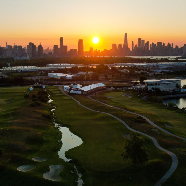 Aerial view of the golf course with Manhattan skyline and sunset in the background