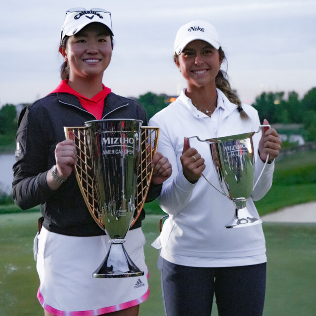 Two women in white hats holding trophies