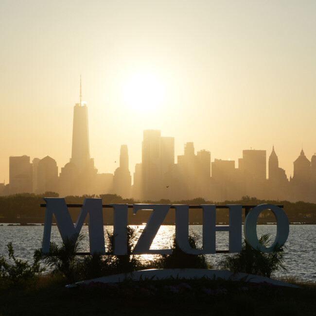 Mizuho sign with the Manhattan skyline and sun in the background