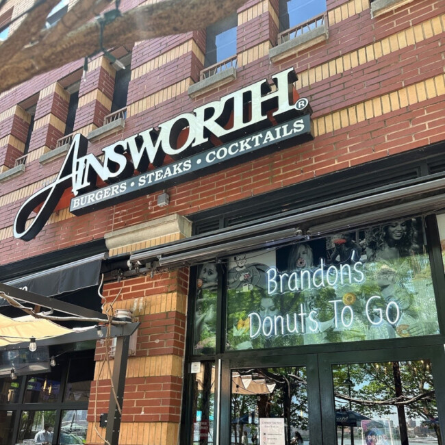 Exterior of The Ainsworth with a sign in the window that reads "Brandon's Donuts To Go"