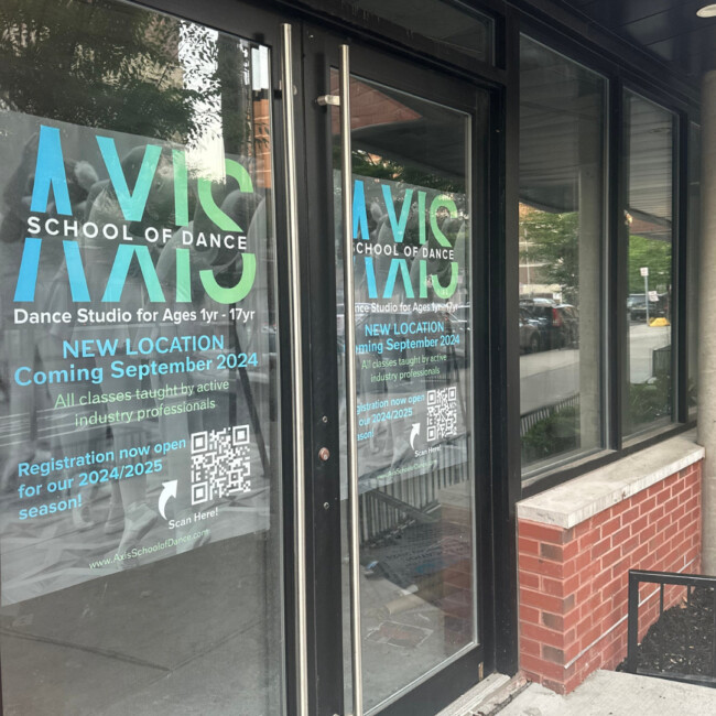 View of glass doors with information about AXIS School of Dance and the new location coming in September 2024