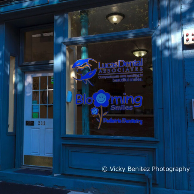 Entrance to Lucas Dental with signs in the window that read "Lucas Dental Associates" and "Blooming Smiles"