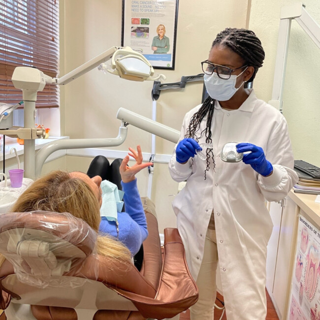 Dr. Lucas with a mask and gloves talking to a patient in the dental chair