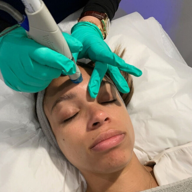 Teal-gloved hands giving a woman a facial treatment