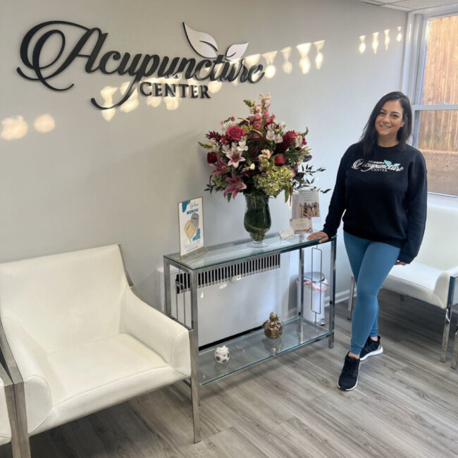 Ani Balan, owner and head acupuncturist at NJ Acupuncture Center, stands at a table holding a bouquet of flowers.