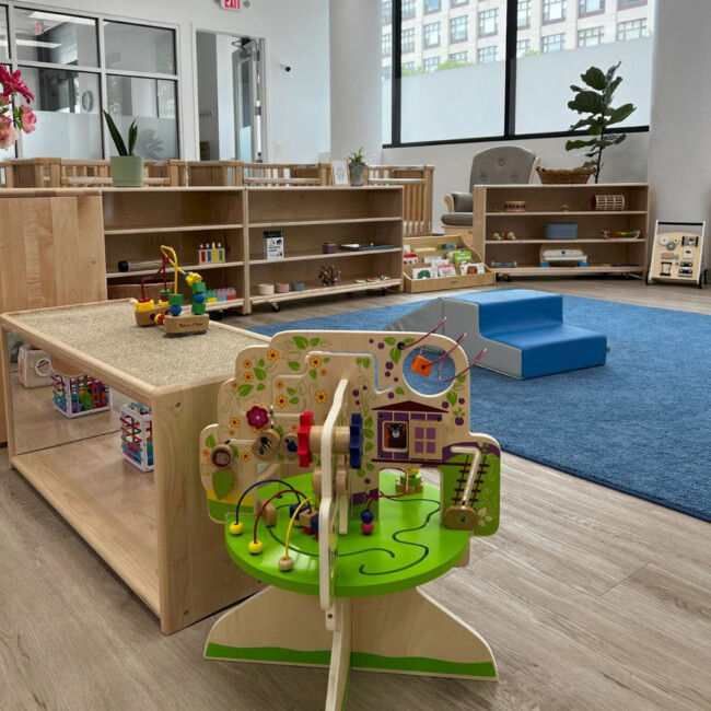 Classroom with wood shelves, toys, and blue carpet