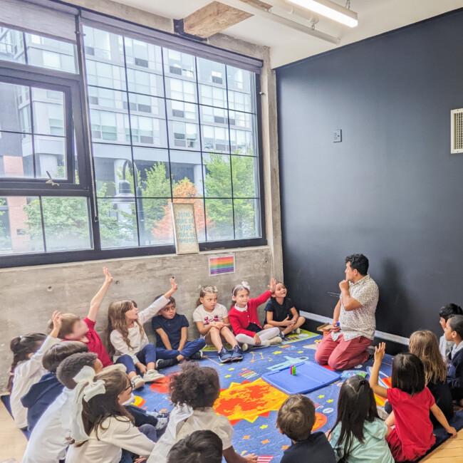 Students and teacher sitting in a circle on the ground